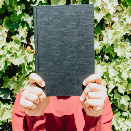Super close up of two hands grabbing and reading a book during a super sunny day, relax and mental health concepts